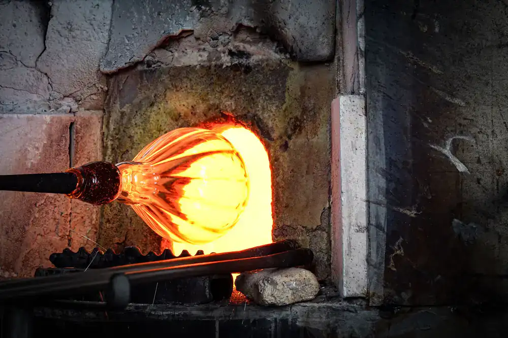 Glowing custom glass piece being shaped in the hot shop