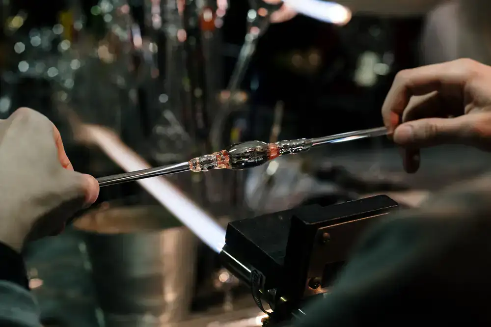 A group observing a glassblower shaping hot glass