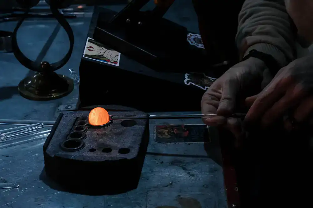 Participant shaping glowing hot glass in the studio